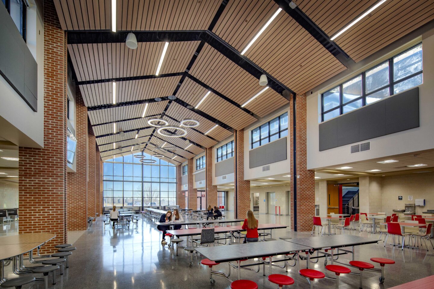 The large cafeteria features clerestory windows and is anchored by floor-to-ceiling windows