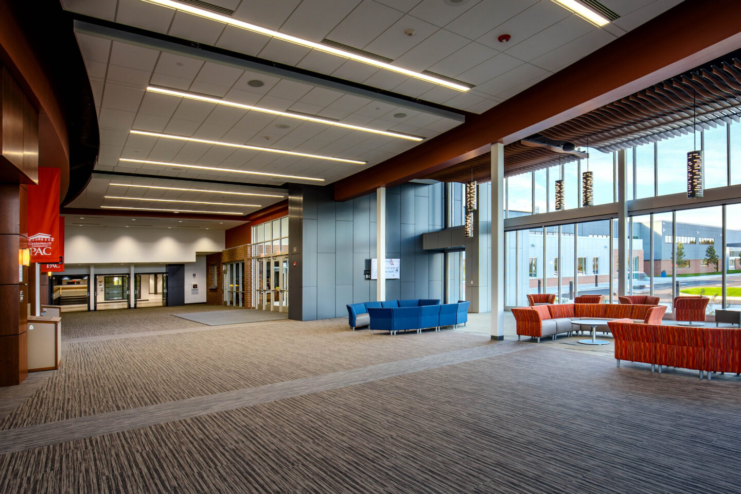 A tall ceiling, wall of windows, and sophisticated light fixtures complement comfortable seating in the lobby