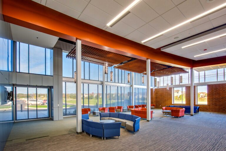 A tall ceiling, wall of windows, and sophisticated light fixtures complement comfortable seating in the lobby