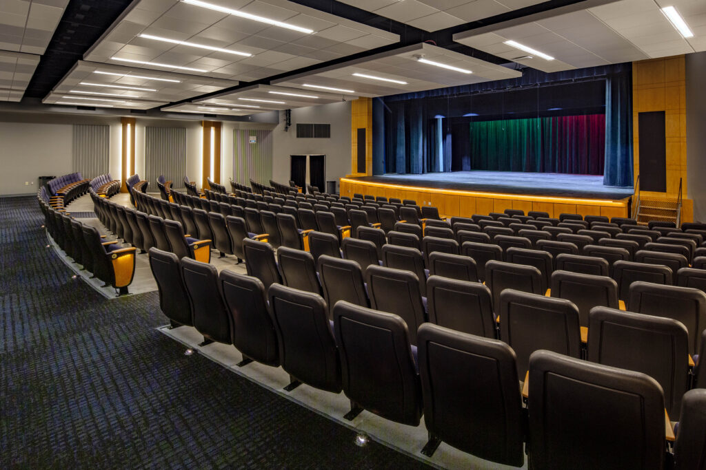 A view over rows of seating toward the stage of the performing arts center at Northern Ozaukee School District