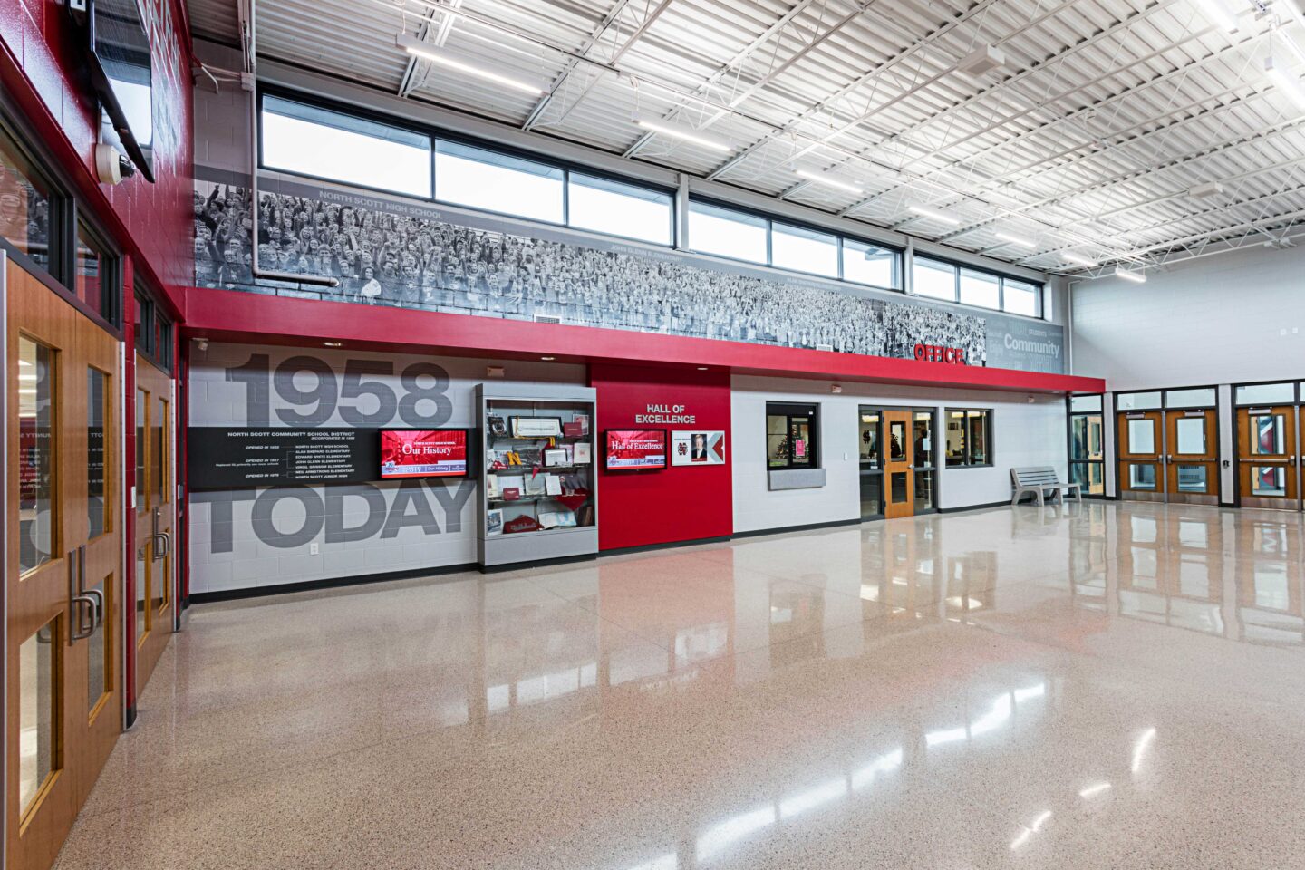 A view of one branded wall of the school's Hall of Excellence, featuring a trophy case and digital screens