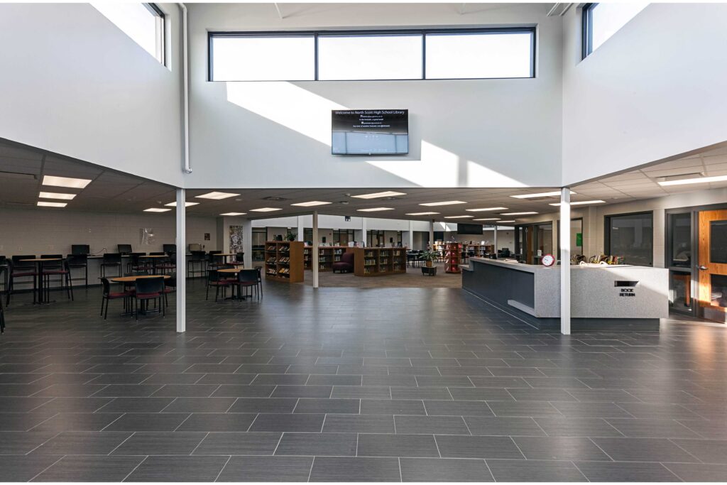 A view of the library entrance with clerestory windows overhead, tables at the left, and the circulation desk at the right
