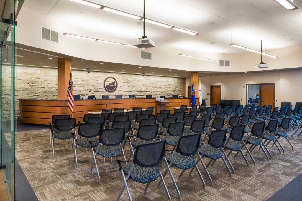 The Oak Creek seal hangs above the dais in a brightly lit chambers room for the common council