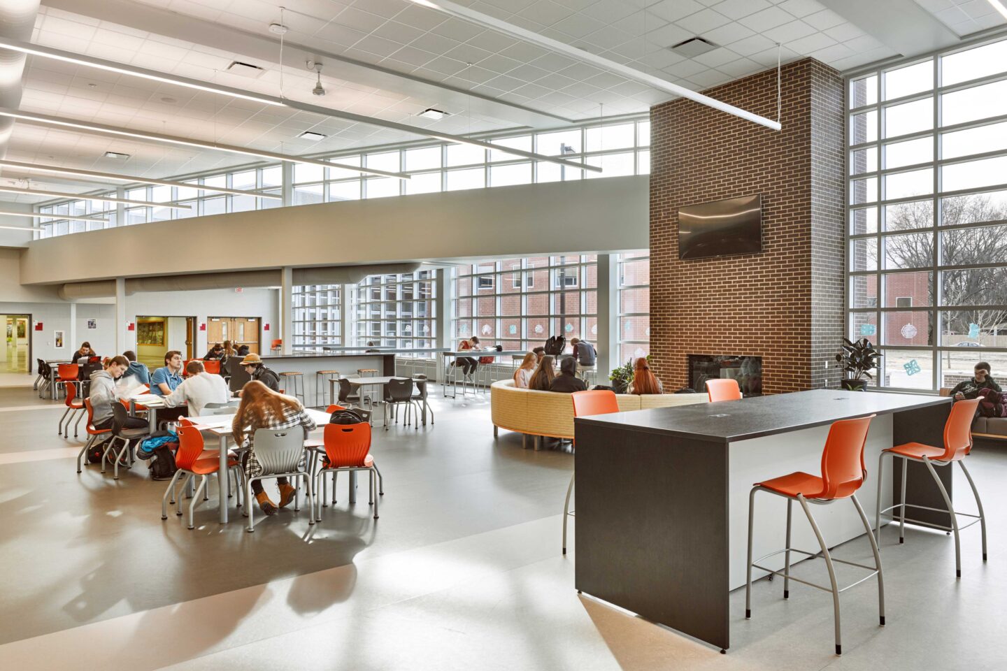A view of students together in the lounge seating area near the cafeteria, which features large windows for ample daylight