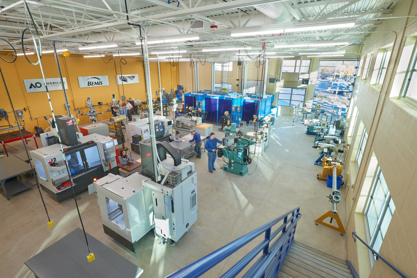 A view from the mezzanine of an active, well equipped manufacturing training room with ample windows at Sheboygan North High School