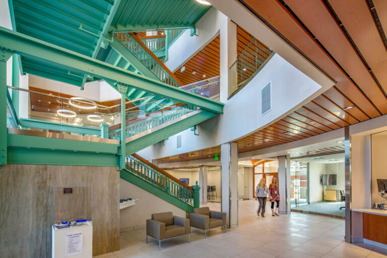 A modern entryway surrounds a historic, green painted staircase at Sheboygan City Hall