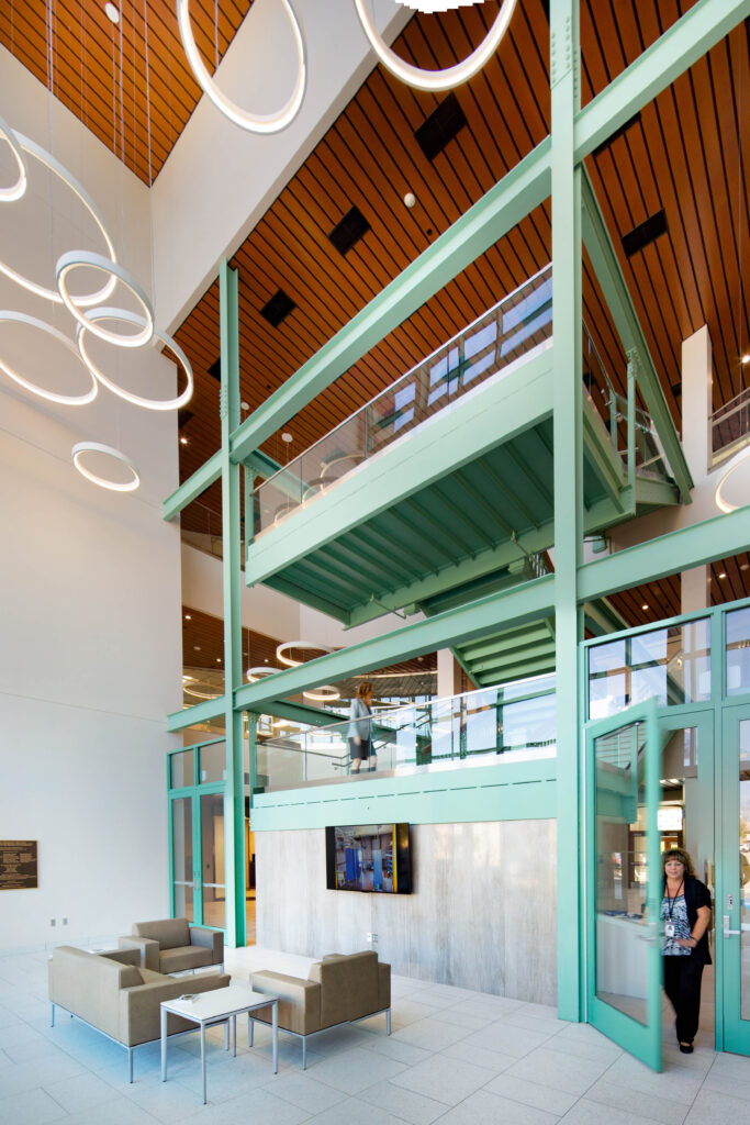 A high ceiling with modern, circular lights connects to a historic staircase in the Sheboygan City Hall atrium