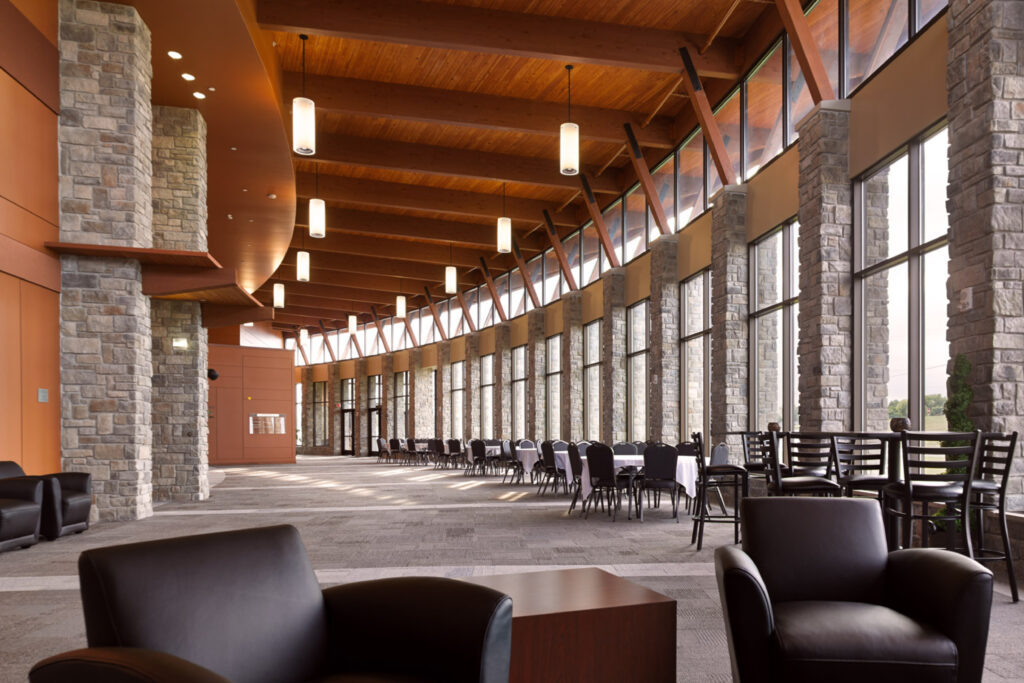 A curving stone and glass wall surrounds an open event lobby