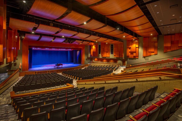 This view of the renovated auditorium stage and seating also showcases the elegant wood-toned acoustic ceiling and wall panels