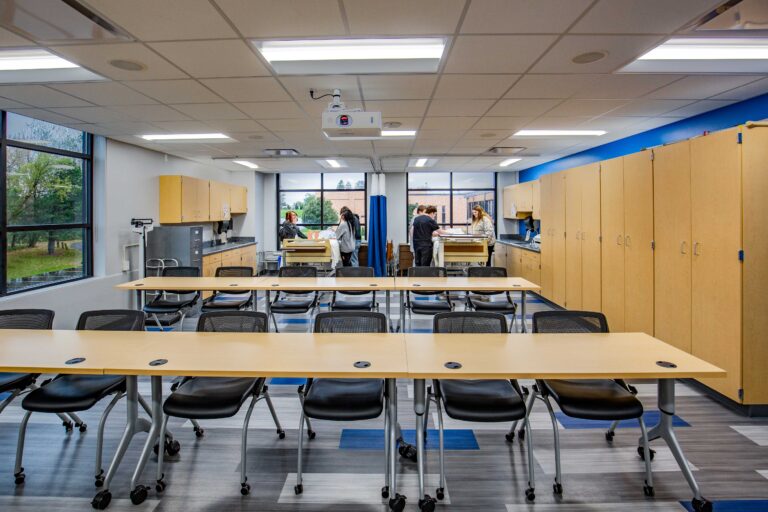 Nursing students do hands-on work in a classroom area with large windows