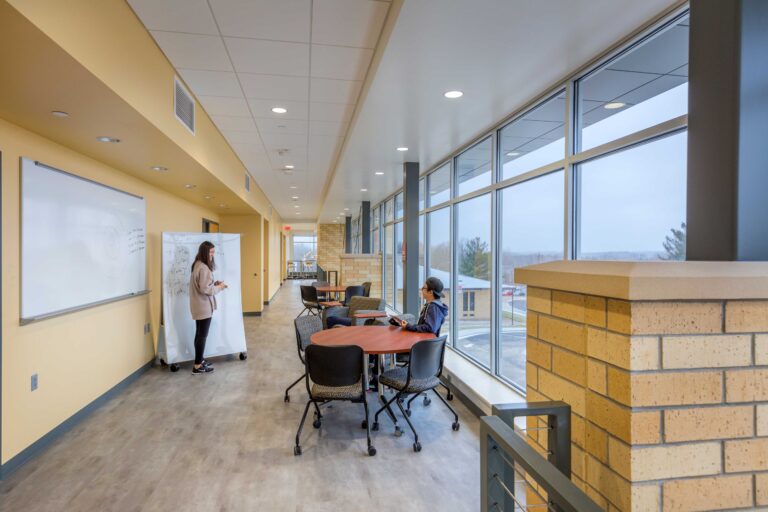 Students collaborate in a gallery space lined with whiteboards and large windows