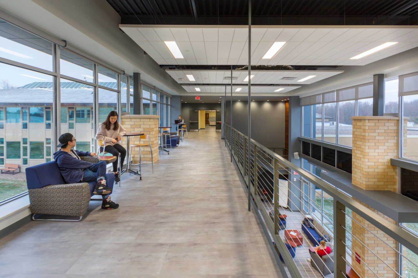 Students study in wide, windowed spaces lofted above a commons