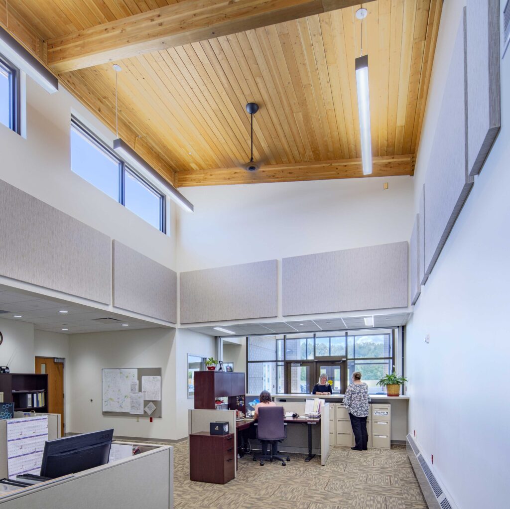 A vaulted, wooden ceiling tops off a lobby space with modern lighting and ample windows