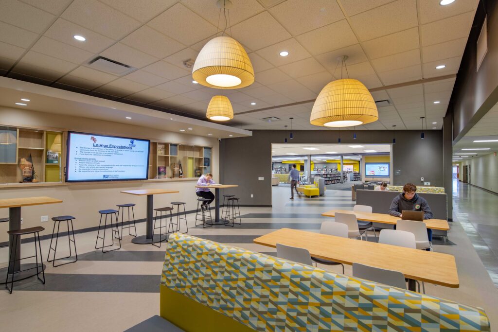 Cafe-style seating fills a lounge area, as students study in a space adjacent to the larger library