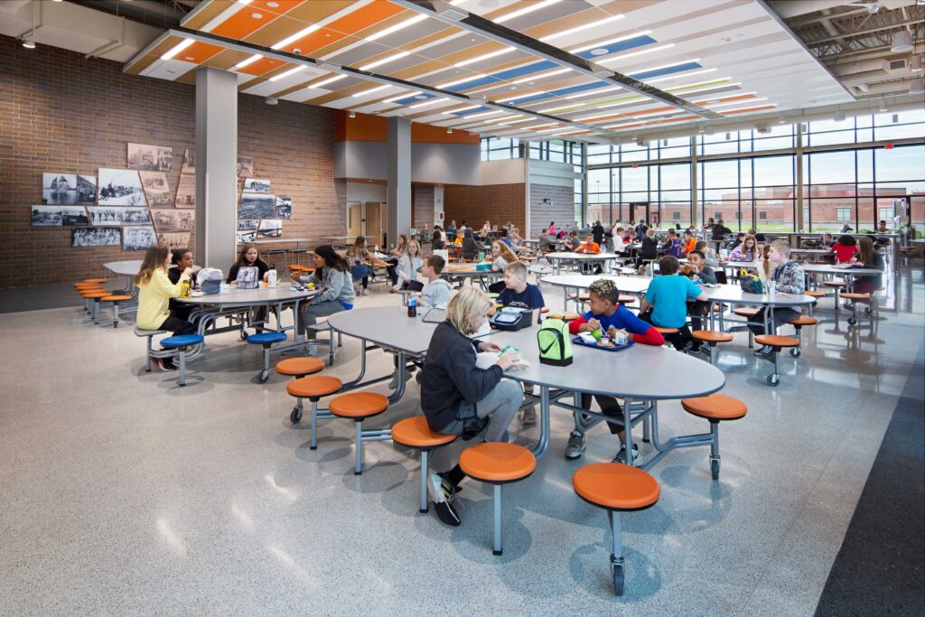 Students enjoy lunch in the cafeteria, which features large windows and colorful ceiling tiles