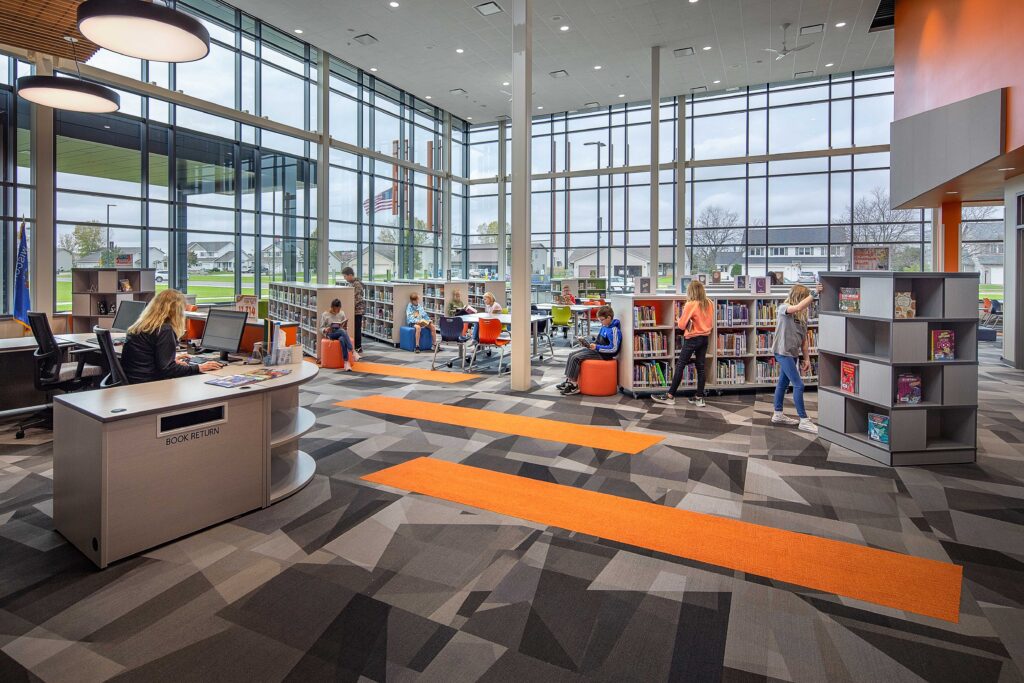 Students select books from the stacks of the school library, which features a floor-to-ceiling windows that offer sweeping views of the nearby neighborhood