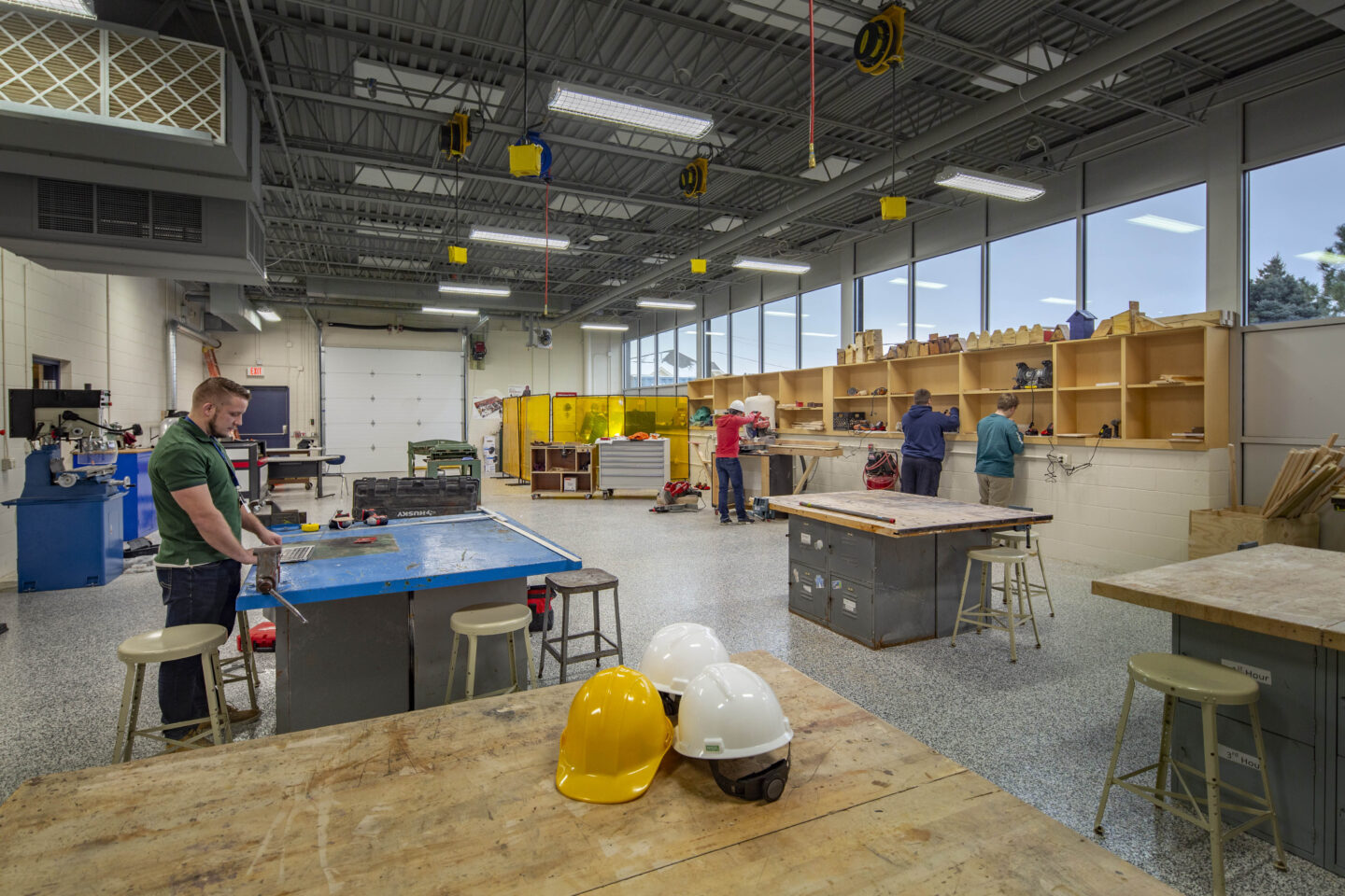 A large shop with windows and a garage door holds a variety of equipment for students to learn trades at Whitnall High School