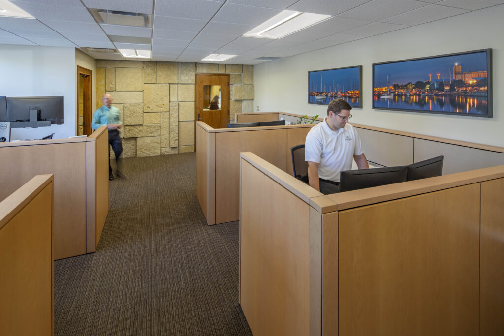 Individuals work at office stations surrounded by art and natural light