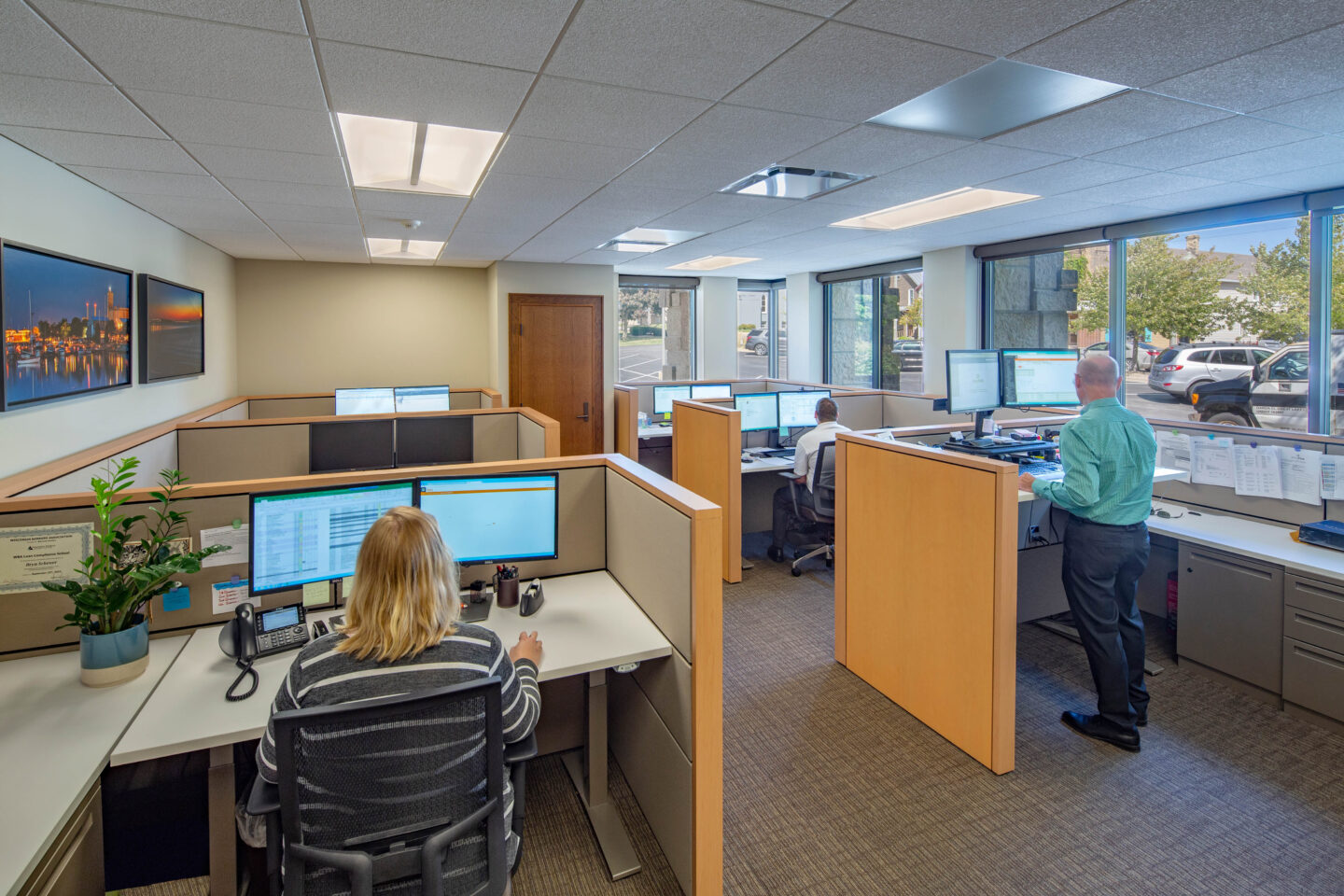 Individuals work at office stations surrounded by art and natural light