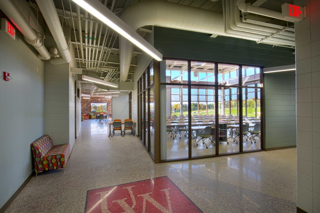 A lecture room flows with large windows into the hall and the outdoors