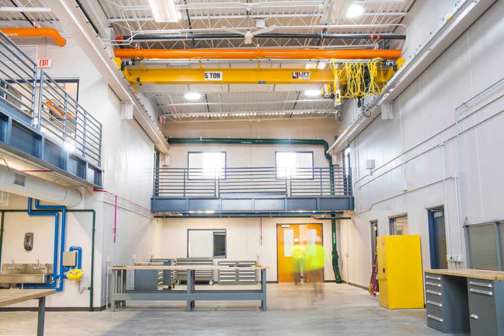 People walk through a high-ceilinged facility with pipes running along the ceiling at the Madison Metropolitan Sewerage District