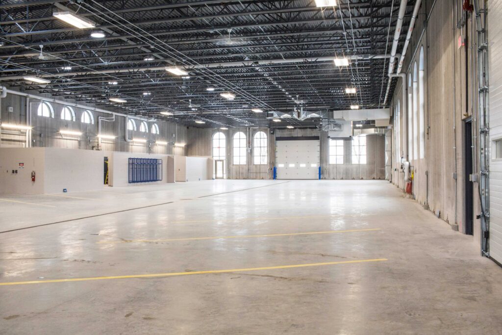 Arched windows surround an open garage area with concrete floors and beamed roof