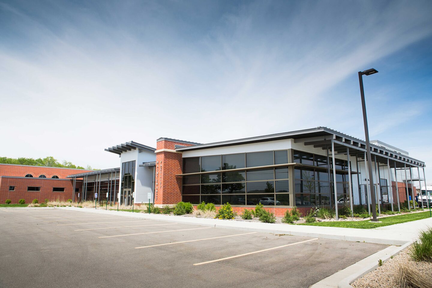 Exterior view of a low building with walls of windows and garage facility in the background