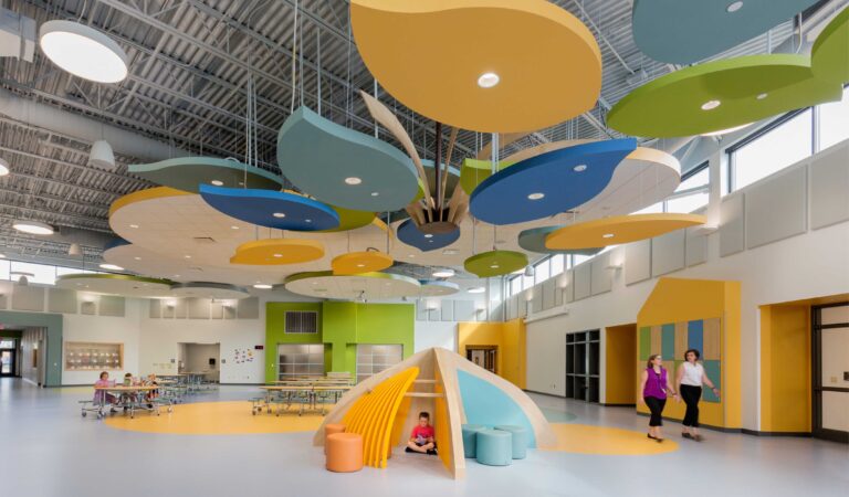 Students and teachers pass through the "town square," which features a colorful installation at its center that resembles a tree canopy.