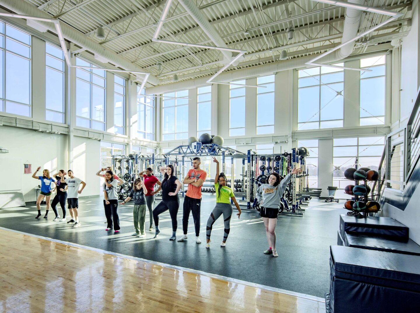 Students pose in the fitness center with a view of the space's large windows in the background