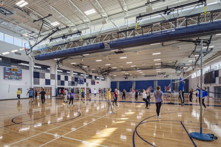 A physical education class plays volleyball games in the multi-station gymnasium