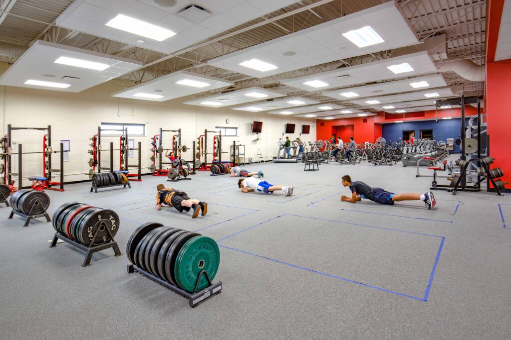 Students exercise in the fitness room, which features weight and cardio machines.