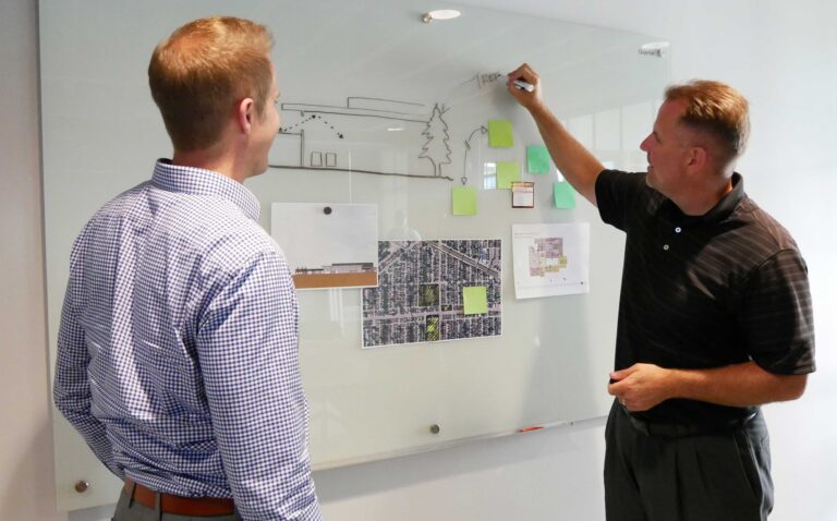 Two Bray team members work at a dry erase board as they collaborate on a project