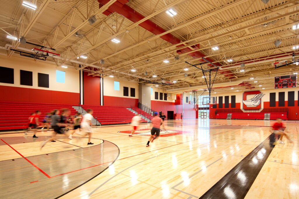 Oostburg High School gym with logo on the back wall and students running