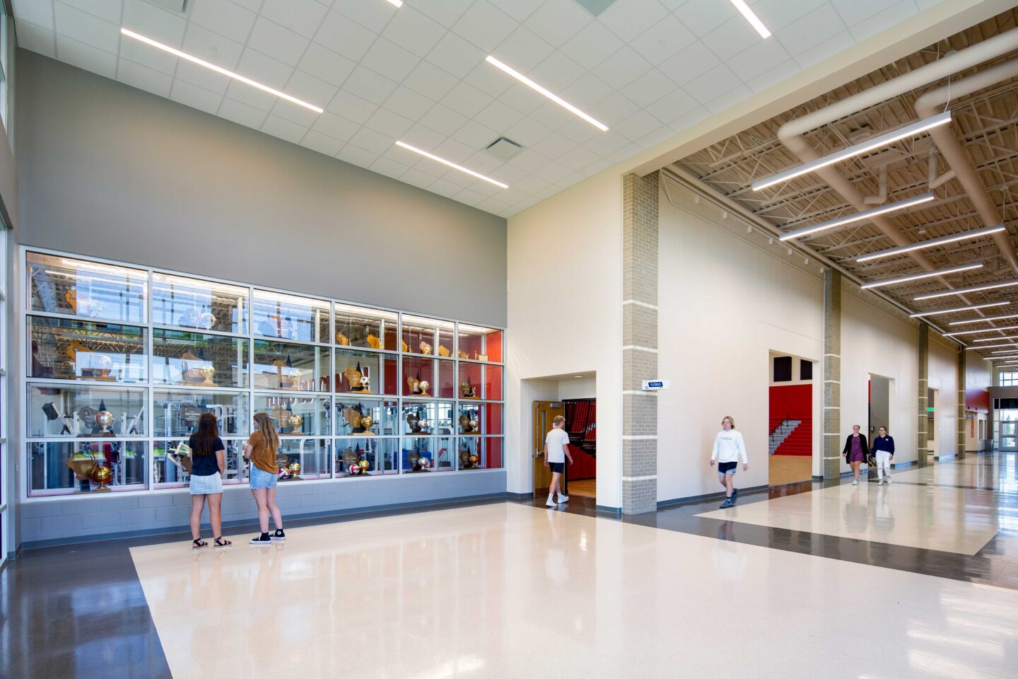 Oostburg High School hallway into gym featuring the trophy case wall