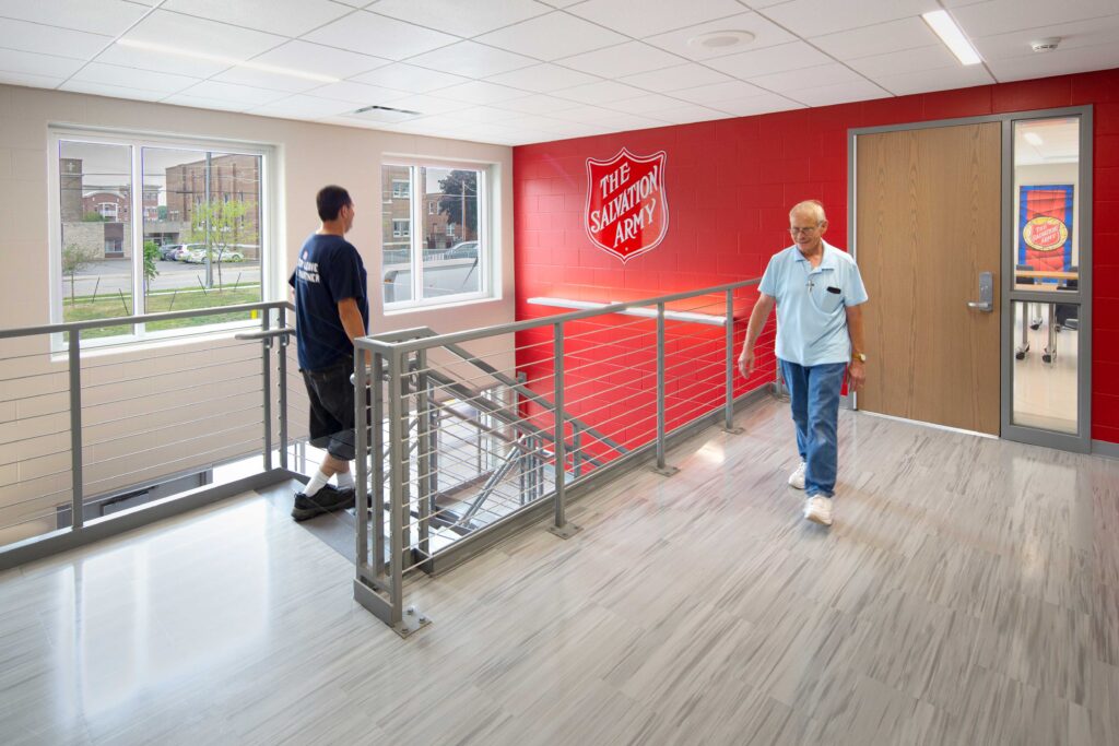 Salvation Army Oshkosh Staircase with shield logo on the back wall and people walking