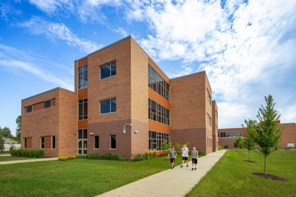 JC McKenna Middle School Exterior south side of the building with three students walking on the sidewalk