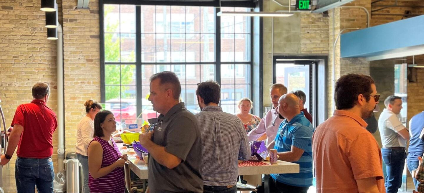 Small groups of people gather around a countertop full of food at the Bray office