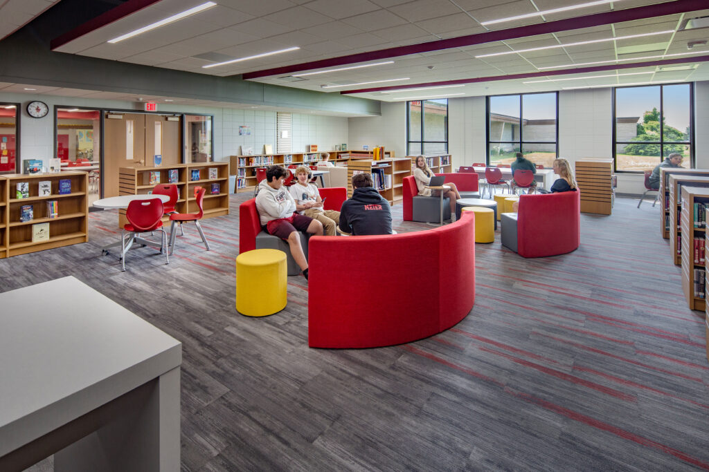 The school library with large windows and a variety of furniture to accommodate individual and group work.