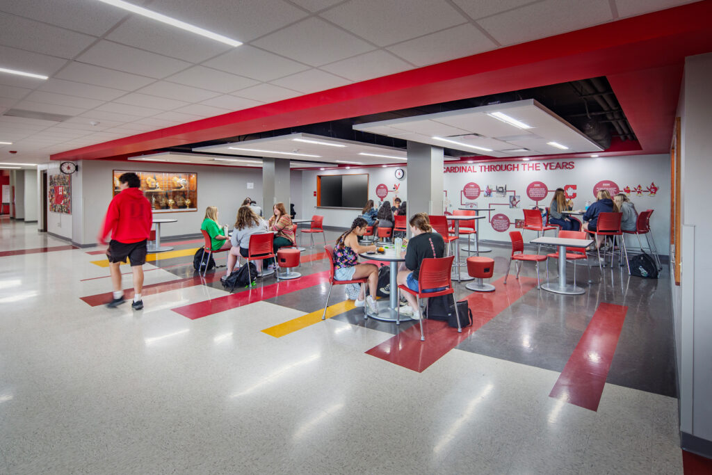 Student lounge with flexible furniture, a trophy case, and a history timeline on the back wall