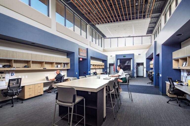 Police squad room with desks, clerestory windows, and TV's