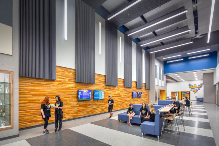 Events lobby at Vel Phillips Middle School featuring the reclaimed wood wall with monitors and flexible furniture.