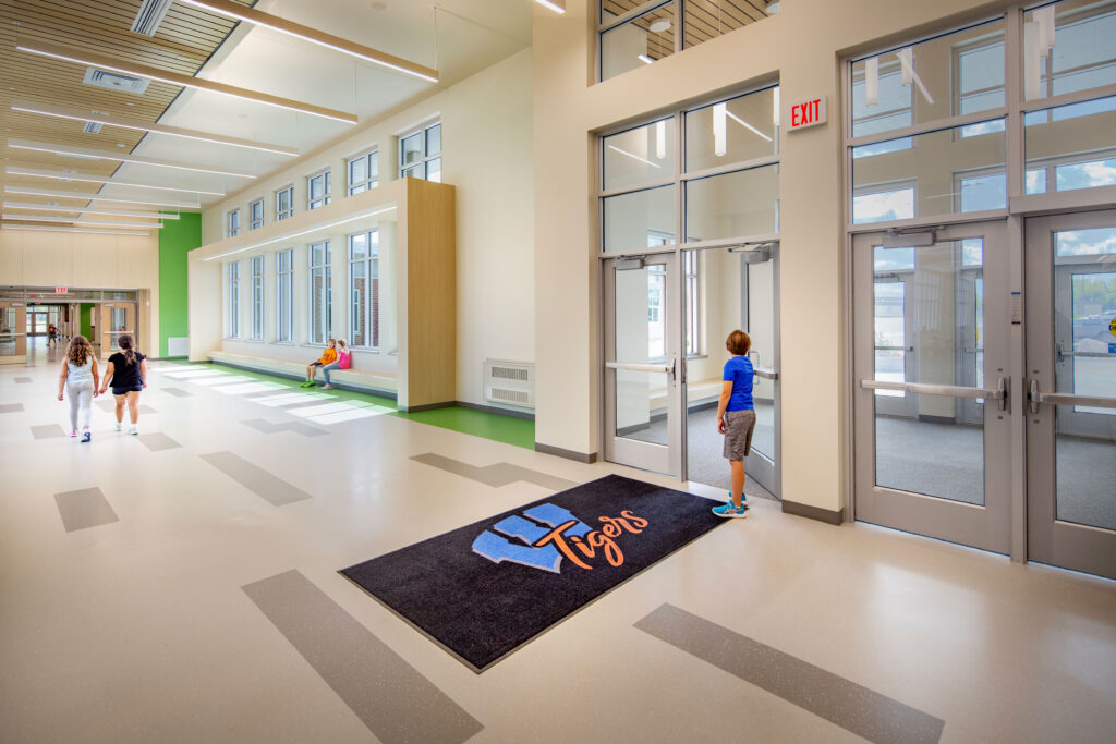 Lobby at Wrightstown elementary school with large windows bringing natural light into the hallway and a bench for sitting