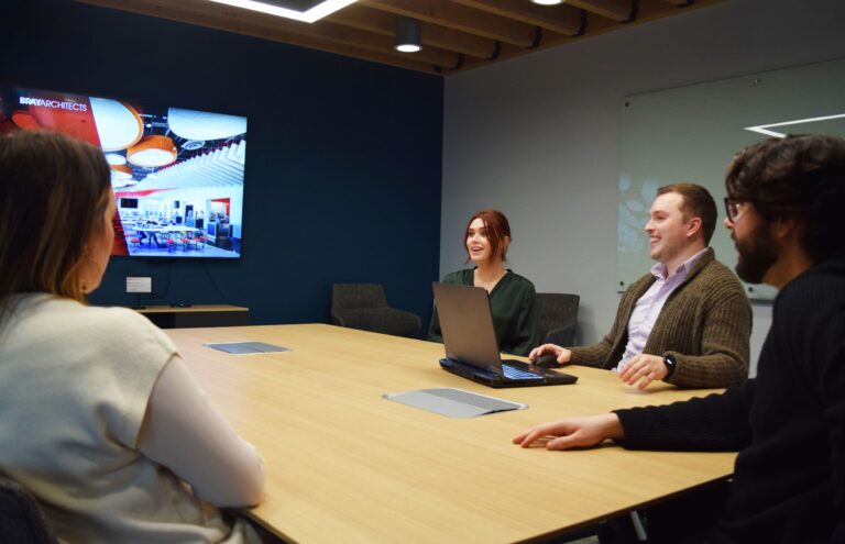 Two Bray team members look over a large document in a conference room at the Bray Architects office.