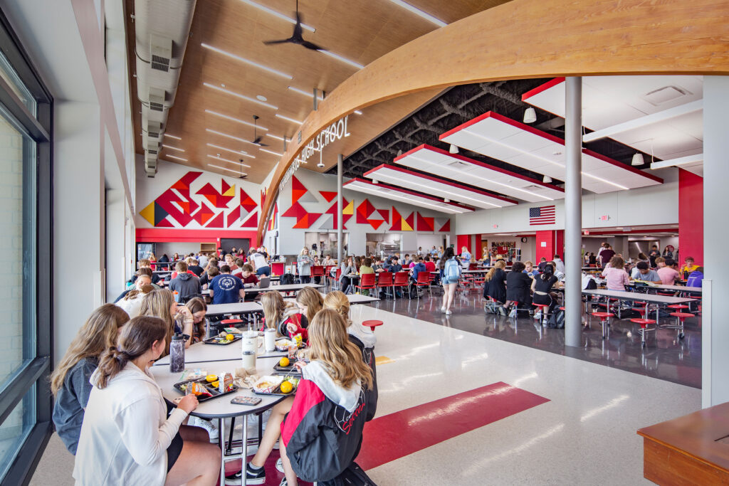 Cafeteria with colorful acoustic panels on the wall and archway with school name