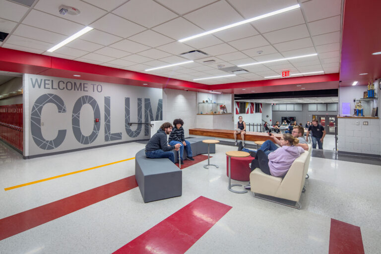 Upper commons area with school name enlarged on wall. Also, a view into lower commons is seen.