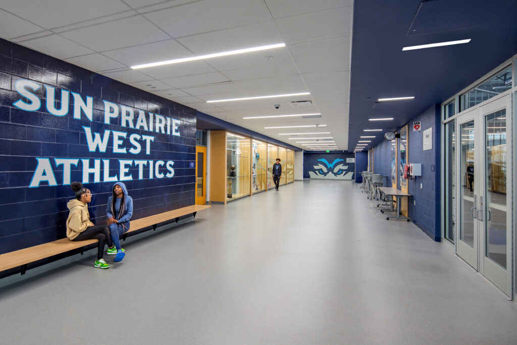 Athletic commons hallway with doors leading the pool and to the auxiliary gym. A trophy case is displayed on the gym wall.