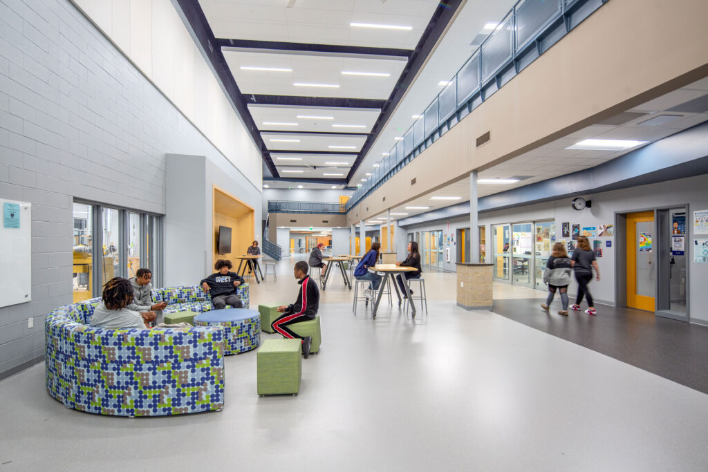 Knowledge market corridor with second floor overlook and stairs in the back. Flexible furniture and tables fill the space