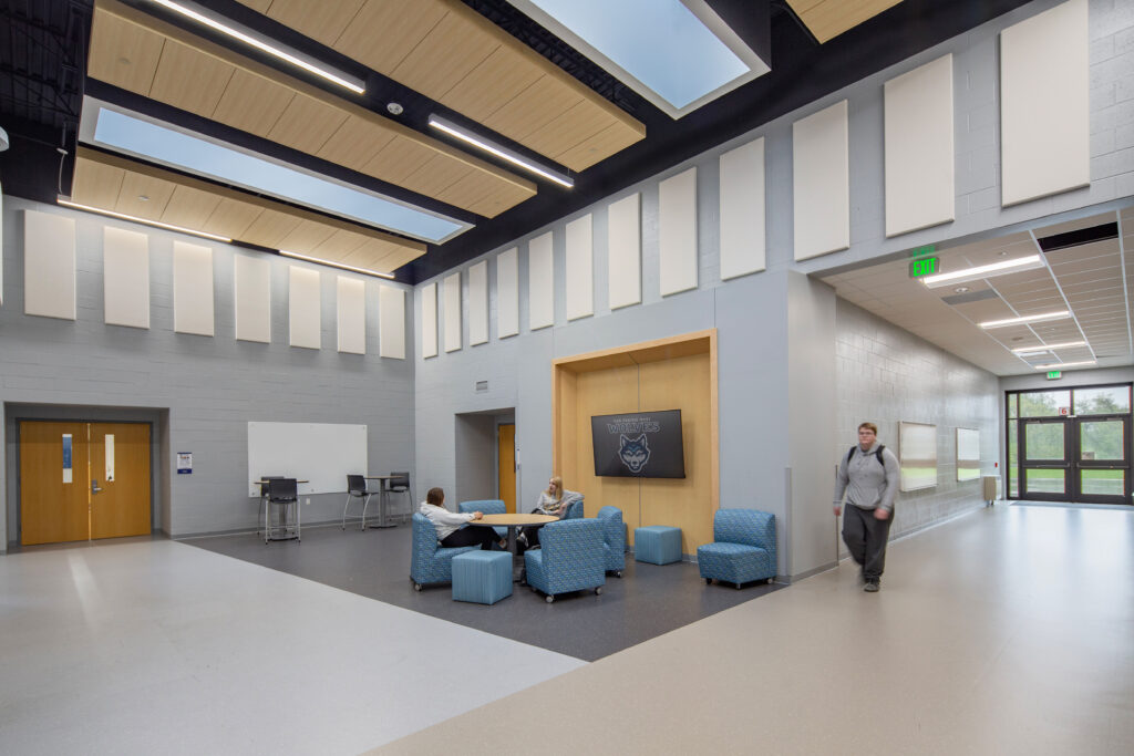 Music commons area with doors leading to choir and band room. Acoustic paneling is surrounding the walls.