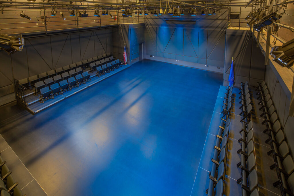 Black theater box with blue lighting and a cat walk