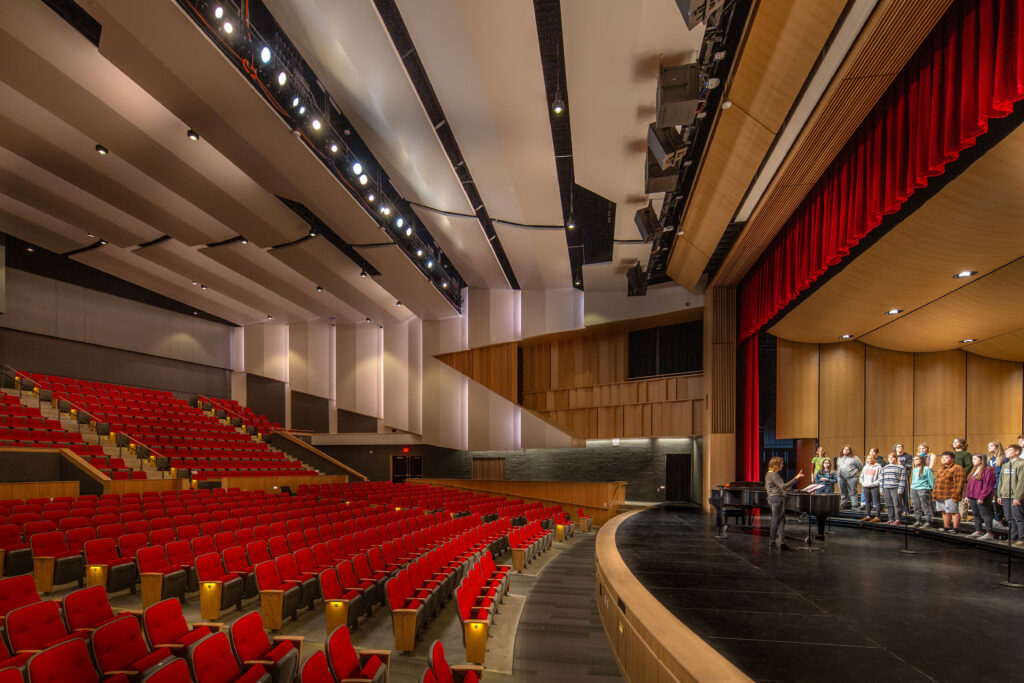 The side of the stage and the red theater seating in the auditorium at Neenah High School